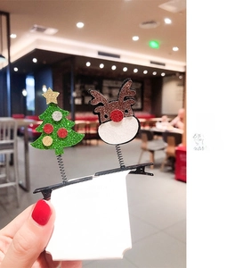 Detail of glittery Christmas tree and reindeer hair clips on white card holder
