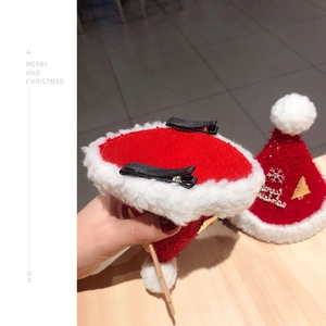 Detail of two red plush Christmas hat hair clips with festive gold snowflake patterns