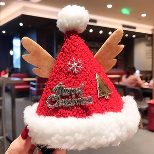 Detailed view of a mini red knitted Christmas hat hair clip with festive ornaments