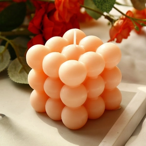 Candela profumata a cubo di bolle color pesca per decoro con design geometrico e luce calda