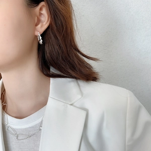 Close-up of twisted 925 sterling silver earrings and rectangular link chain on a model