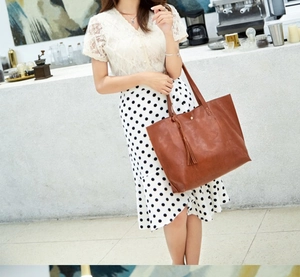 Brown vintage oil wax leather bucket bag with tassel detail shown in a lifestyle street shot