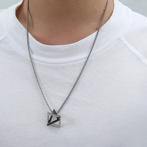 Detail of interlocking silver and black triangle pendants on a silver box chain necklace