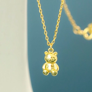 Macro shot of 3D polished golden bear pendant with a delicate link chain necklace