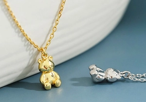 Macro side view of polished 3D teddy bear pendant necklaces in gold and silver finish