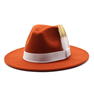 Vue détaillée du chapeau fédora orange en feutre avec ruban blanc et plumes