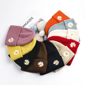 Collection of colorful knitted beanies with daisy embroidery in various vibrant colors