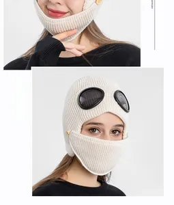Close-up of warm white knit aviator hat featuring dark goggles and wooden buttons