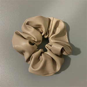 Detail of beige faux leather scrunchie showing soft texture and elegant pleats