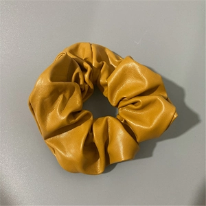 Macro detail of yellow PU leather scrunchie showing premium texture and soft finish