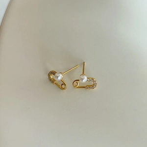 Detail of gold safety pin earrings with white pearls and sparkling rhinestones