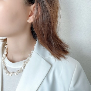 Close-up of baroque pearl necklace and golden safety pin earring on a female model