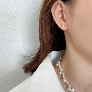 Close-up of gold safety pin earrings with small pearls and crystals on a model