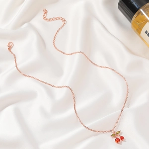 Close-up of rose gold cherry pendant necklace with red and green cubic zirconia stones