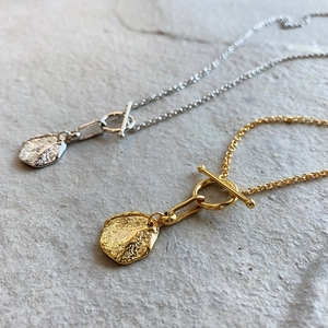 Close-up of gold and silver hammered round pendants with vintage T-bar toggle closures
