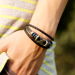Multilayer braided leather bracelet with X-shaped metal charm and blue beads on wrist