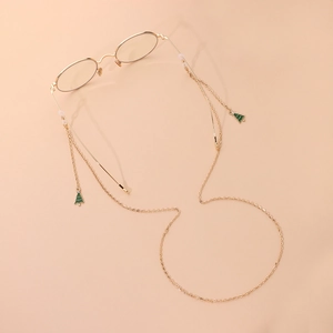 Golden metal glasses chain featuring green enamel Christmas tree charms on a beige background