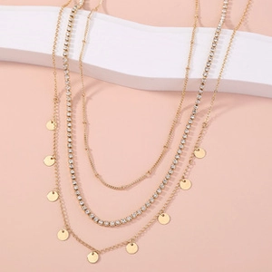 Macro detail of triple-layered gold necklace with sparkling rhinestones and metal sequins