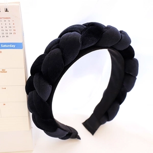 Detailed close-up of a handmade black braided velvet headband with thick woven texture