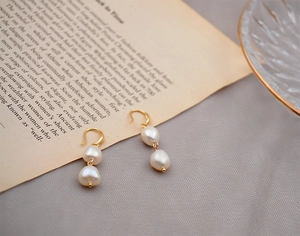 Detailed macro view of baroque freshwater pearl drop earrings with elegant golden hooks