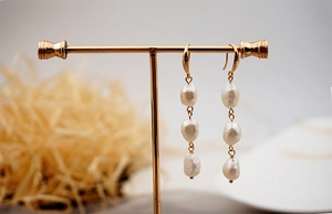Detail view of triple baroque freshwater pearls hanging on a gold-tone T-shape jewelry stand