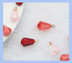 Macro shot of resin pomegranate seed pendants in red and pink with gold loops