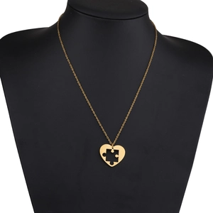 Détail du collier à pendentif cœur puzzle doré exposé sur un buste noir chic