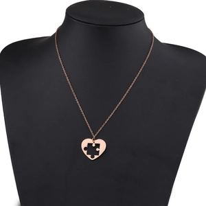Détail du collier puzzle en forme de cœur fini or rose sur un buste noir chic