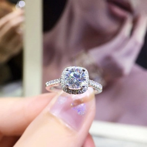 Close-up of a silver halo diamond ring with round center stone and pave band details