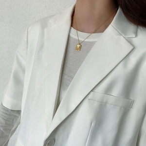 Detail of minimalist golden hammer-textured rectangular pendant necklace on neck