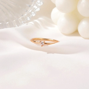 Minimalist gold heart ring featuring a sparking zircon stone on a white silk background