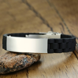 Detail of black silicone bracelet with polished silver stainless steel plate on rock background