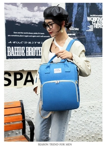 Close-up of blue canvas diaper backpack with multiple zippers and top handle details