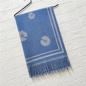 Detail of blue cashmere feel scarf featuring grey daisy floral patterns and fringed edges