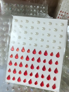 Detail of adhesive white pearls and red teardrop rhinestones for facial makeup and nails