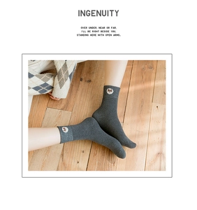 Detailed view of grey thermal crew sock with small dog embroidery on wood floor