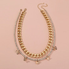 Detail of layered gold Cuban chain and silver rhinestone tennis necklace with butterflies
