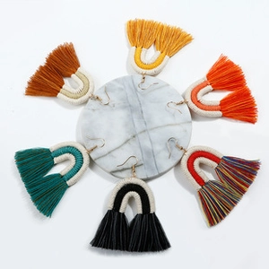 Vue détaillée de boucles d'oreilles pompons en coton tissé coloré avec crochets dorés