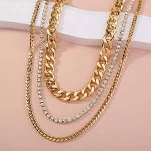 Detail of layered gold chains with sparkling white rhinestones and textured metal finish