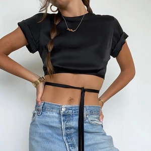 Detail of black crop top featuring stylish rolled sleeves and chic waist tie design