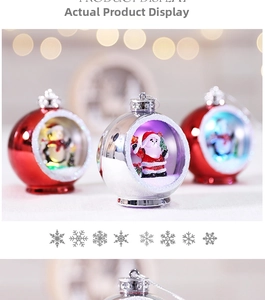 Close-up of glowing Christmas ball ornaments with Santa and penguin miniature scenes