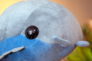 Detailed close-up of the plush toy featuring a glossy black eye and soft blue fabric texture