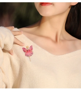Detailed view of an elegant ballet dancer brooch with pink rhinestones on a beige sweater