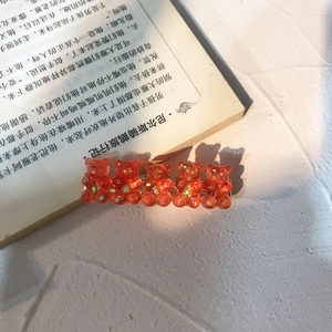 Detail of orange resin bear hair clip with colorful sequins and silver metal base
