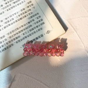 Pink bear hair clip with translucent resin and glitter on an open book, cute style