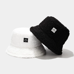 Teddy fleece bucket hats in black and white with a smiley face patch for winter warmth