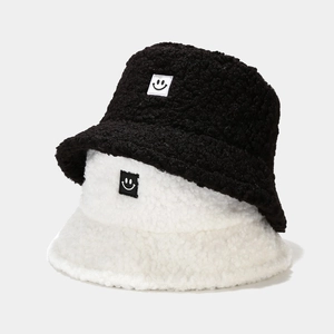 Detail of teddy fleece bucket hats in black and cream featuring a smile patch