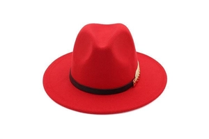 Detail of red wool felt fedora featuring a black ribbon band and golden feather ornament
