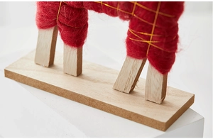 Close-up of wool felt Christmas deer with natural wood base and gold thread detail