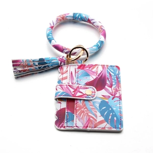 Detail of tropical print card holder wristlet with gold snap button and tassel charm